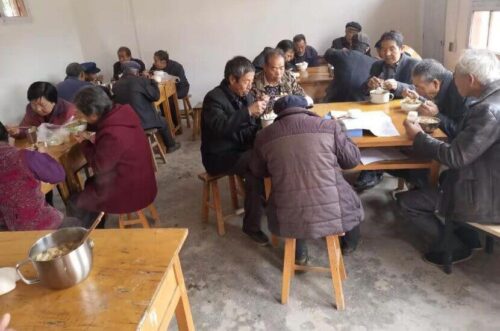 Elderly villagers eating together in an Amity sponsored canteen