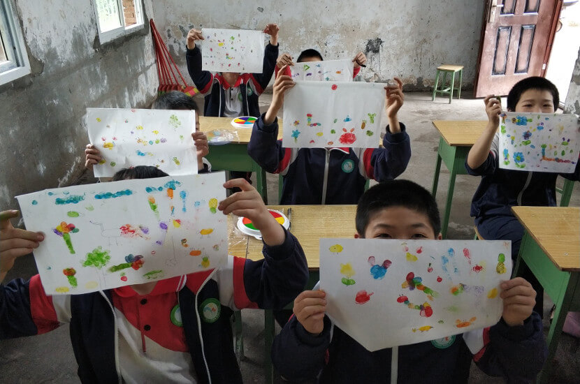 Children showing their paintings into the camera