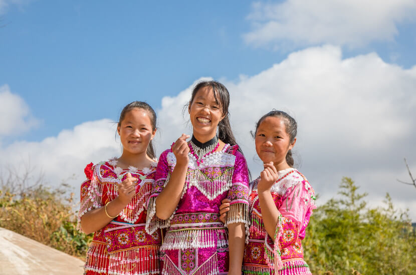 Three happy girls in traditional clothing showing hearts