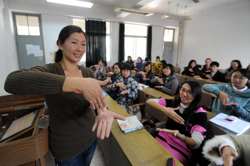 A female teacher is teaching sign language to students