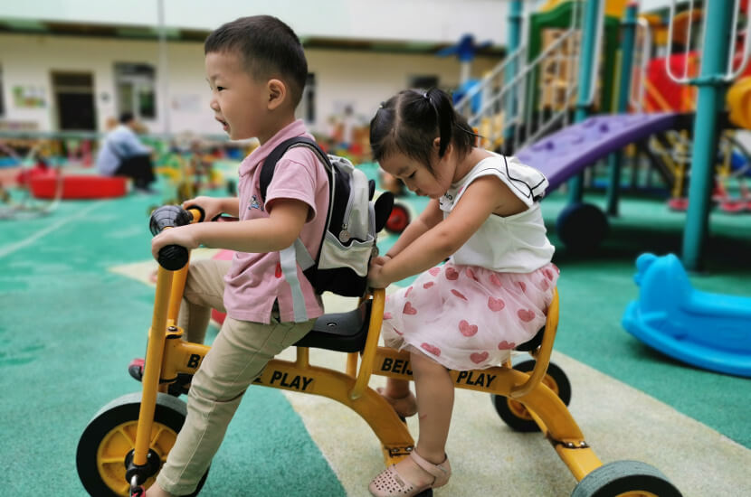 A young deaf boy and a girl riding a tandem bicycle at Amity's integration program