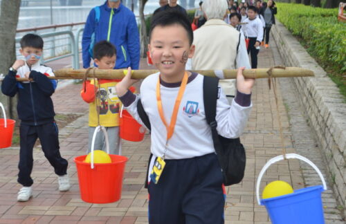 A student is carrying water buckets during the Walk for Living Water event