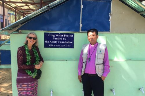 Debbie and the Bishop of Diocese of Toungoo standing in front of the new sanitation facilities built by Amity's water program