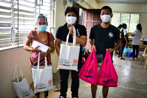Elderly women and two men holding ACT Alliance/Amity/NCCP bags with Torch Program supplies