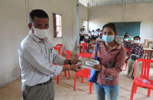Cambodian local partner hands over cash incentives to mother of a student