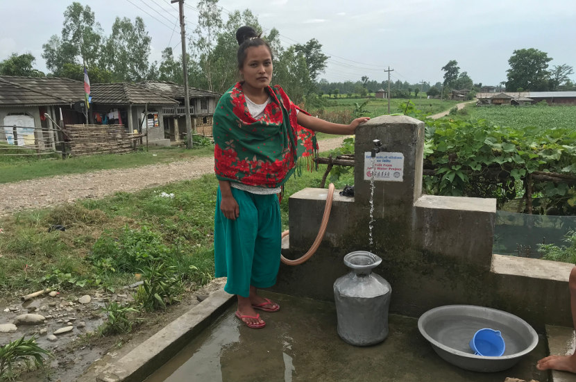 Village women in Myanmar stands next to a newly constructed water tap