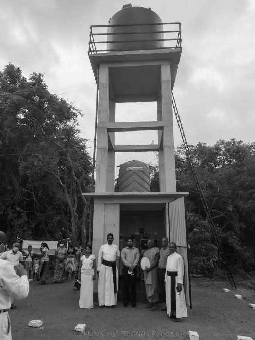 Picture of late  Mr Suren Goonesekara in front of a water tower provided by Amity Living Water